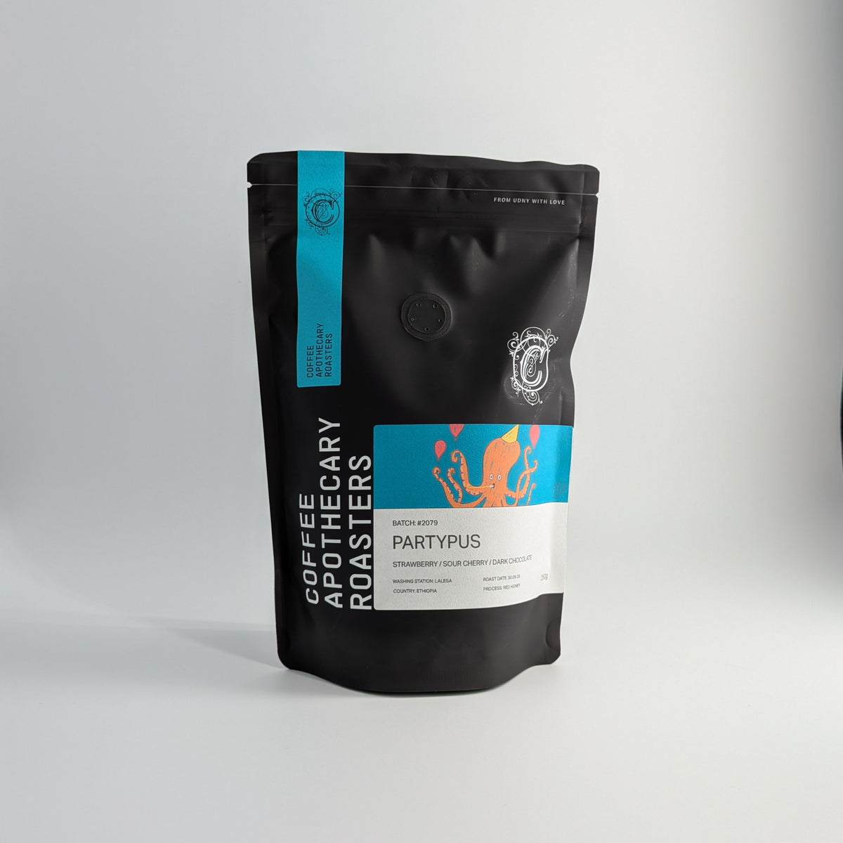 A black stand-up pouch of Coffee Apothecary Roasters 'Partypus' coffee, featuring a bright turquoise and white label with orange splash graphics, set against a neutral light gray background.