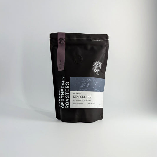 A black stand-up pouch of coffee from Coffee Apothecary Roasters, specifically the Starseeker variety, set against a plain light gray background.